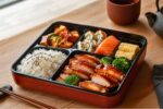 Authentic Japanese Bento Box with Teriyaki Chicken, Fresh Sushi, Rice, and Traditional Japanese Side Dishes